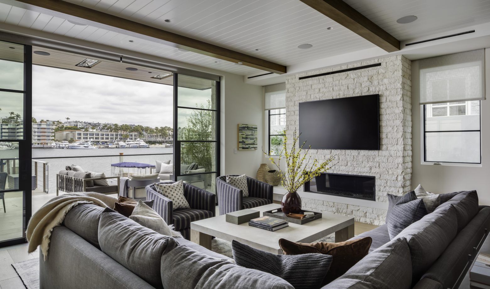 A living room with large open windows overlooking the water and modern furniture.